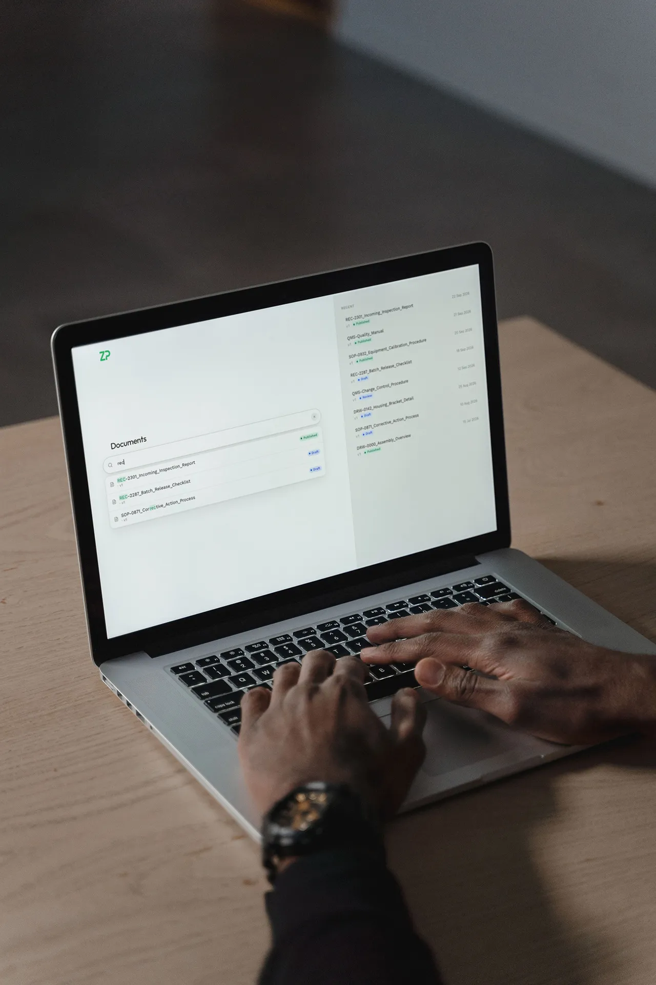 Hands using ZP's internal QMS software on a laptop